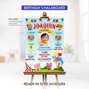 Pode incluir: Um quadro-negro de aniversário azul e vermelho com uma moldura para fotos para o primeiro aniversário de uma criança. O quadro-negro inclui o nome da criança, Joaquin, e detalhes sobre seu primeiro ano, incluindo seu peso, altura, data de nascimento, alimentos favoritos e músicas favoritas. O quadro-negro é decorado com personagens de desenhos animados e uma tenda de circo.