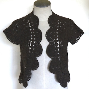 May include: A brown crocheted shrug with a scalloped edge and short sleeves.