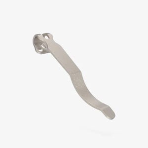 Könnte beinhalten: Ein silberfarbener Metall-Taschenclip mit einem geschwungenen, länglichen Design und einer breiteren Montagebasis. Die Basis verfügt über drei kreisförmige Löcher zur Befestigung, und der Hauptkörper des Clips hat eine glatte, matte Oberfläche mit einer leichten Biegung.
