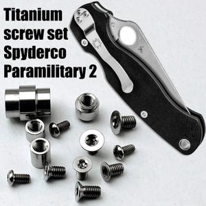 Może przedstawiać: Zestaw tytanowych śrub do noża składanego Spyderco Paramilitary 2, zawierający różne srebrne metalowe śruby, tuleje gwintowane i tuleję osi, pokazany obok noża składanego z czarną rękojeścią i srebrnym klipsem do kieszeni.