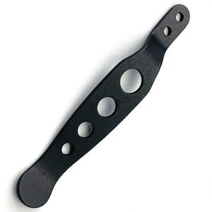 Puede incluir: Un clip de bolsillo de metal negro mate con una forma larga, delgada y ligeramente curva, que presenta cuatro recortes circulares de tamaños variables en fila y dos pequeños orificios de montaje circulares en el extremo superior.