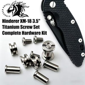 May include: A Hinderer XM-18 3.5" titanium screw set complete hardware kit featuring various silver-colored metal screws and standoffs arranged next to a black textured folding knife handle with a logo and silver hardware accents.