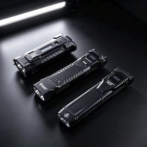 May include: Three black tactical flashlights arranged diagonally. Each device features a rectangular body with a digital display screen, side buttons, and a front-facing lens. The text "LUMIN SHIELD" and "EC27" is printed on the metallic surfaces.