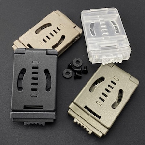 Peut inclure: Trois clips de ceinture rectangulaires en plastique noir, beige et transparent, chacun doté d'une fente centrale verticale avec des encoches de réglage horizontales et des découpes latérales incurvées. Cinq petites rondelles et vis noires sont incluses.