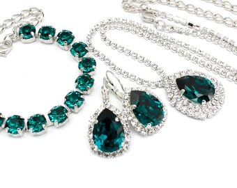 May include: A set of emerald green crystal jewellery featuring a necklace, bracelet, and earrings. The jewellery is made with silver-toned metal and features a teardrop-shaped crystal design.
