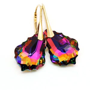 May include: Gold-coloured drop earrings featuring iridescent, multi-coloured crystal pendants. The crystals display shades of purple, orange, yellow, and green. The earrings have a lever-back closure.