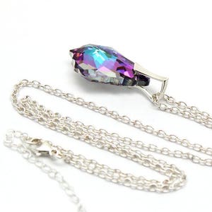 May include: A silver chain necklace with a teardrop-shaped pendant. The pendant is made of iridescent glass with purple, blue, and green hues.