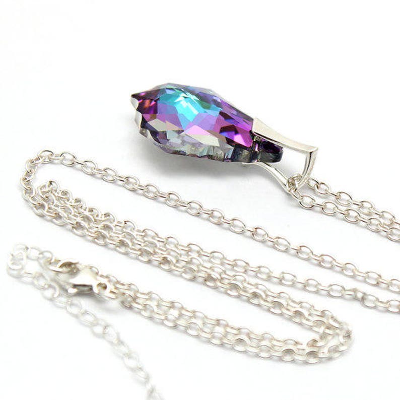 May include: A silver chain necklace with a teardrop-shaped pendant. The pendant is made of iridescent glass with purple, blue, and green hues.