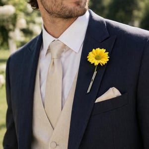 Puede incluir: Un traje azul marino con camisa blanca, chaleco beige y corbata. Una flor amarilla en la solapa. Un pañuelo de bolsillo beige en el bolsillo del pecho. El traje es elegante y parece estar hecho de un tejido fino.