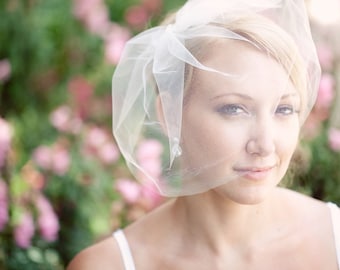 Peut inclure: Une mariée portant un voile blanc à la texture douce et délicate. Le voile est drapé sur sa tête et couvre son visage, créant un look romantique et éthéré.