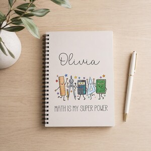 Può includere: Un quaderno a spirale bianco con il nome Olivia in corsivo nero, un'illustrazione colorata di articoli di cancelleria per la matematica animati tra cui righello, compasso, calcolatrice, squadra e libro, e il testo MATH IS MY SUPER POWER in nero.