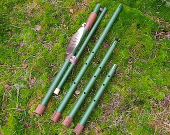May include: Four wooden flutes in various sizes, all painted green with brown leather accents. The largest flute has a feather attached to the top.