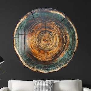 May include: A large, circular wall art piece resembling a cross-section of a tree trunk. The artwork features concentric rings in shades of brown, orange, and teal, creating a natural and rustic aesthetic. The piece is mounted on a dark gray wall.