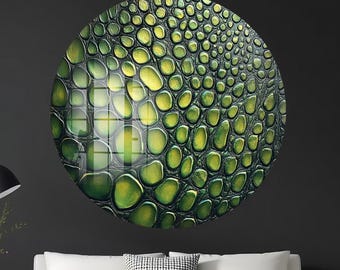 May include: A large, round wall art piece featuring a textured pattern of green and yellow scales, resembling reptile skin. The artwork is mounted on a dark gray wall above a white sofa with wooden legs, creating a modern aesthetic.