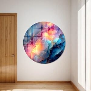 Pu&ograve; includere: Un'opera d'arte murale rotonda con un design astratto. L'opera presenta una miscela di colori, tra cui blu, rosa, arancione e oro. &Egrave; montata su una parete bianca, aggiungendo un tocco moderno all'arredamento.