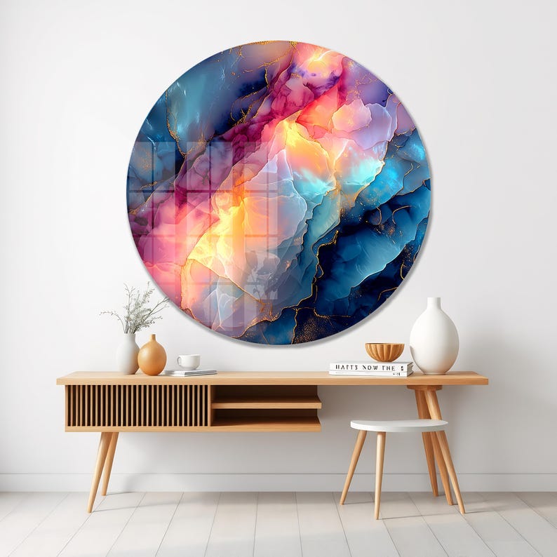 Pu&ograve; includere: Una grande opera d'arte murale rotonda con un design astratto. L'opera presenta una miscela di colori, tra cui blu, rosa e giallo, con accenti dorati. L'opera &egrave; esposta sopra una consolle in legno.