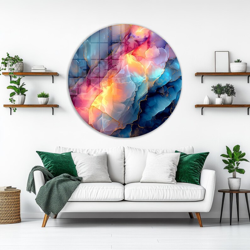 Pu&ograve; includere: Una grande opera d'arte murale rotonda con un design astratto. L'opera presenta una miscela di colori, tra cui blu, rosa, arancione e oro, creando un aspetto vibrante e strutturato. &Egrave; montata su una parete bianca sopra un divano bianco.