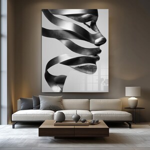 May include: Black and white abstract art print featuring a profile of a face created from flowing ribbons. The artwork is displayed above a modern sofa and coffee table, creating a contemporary living room aesthetic.