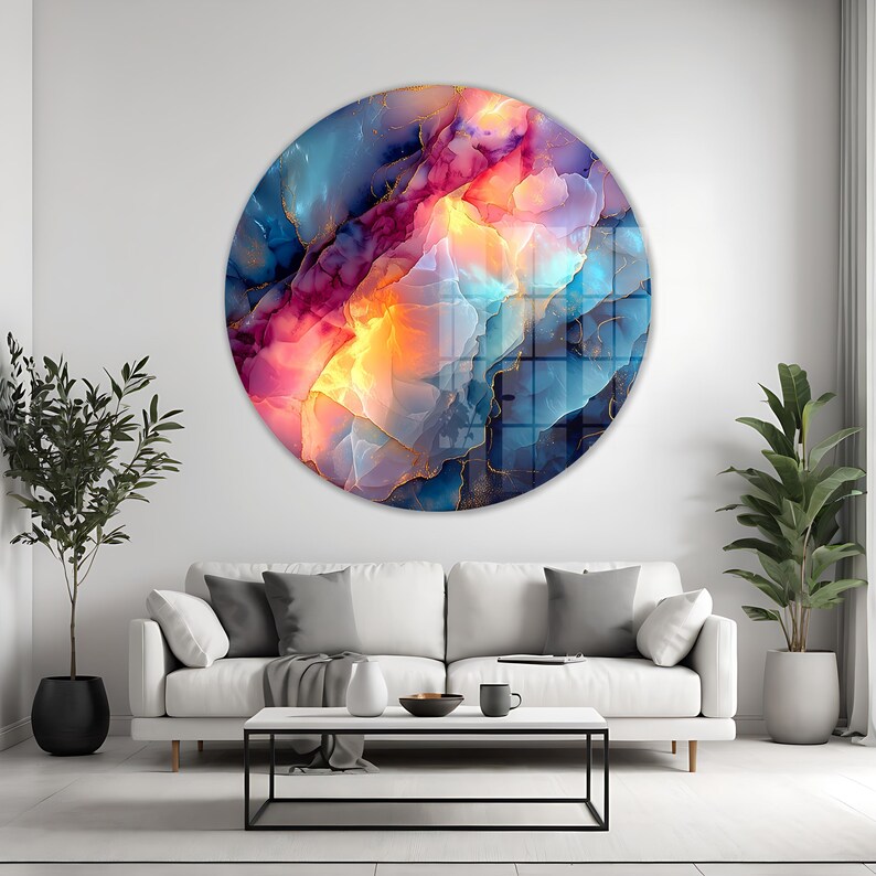 Pu&ograve; includere: Un'opera d'arte murale rotonda con un design astratto dai colori vivaci. Presenta una miscela di blu, rosa, arancione e oro, creando un effetto visivo dinamico. L'opera &egrave; appesa a una parete bianca sopra un divano bianco.