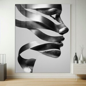 May include: Black and white abstract art print featuring a profile of a face with ribbon-like elements. The artwork is a modern piece with a grayscale color palette, suitable for contemporary home decor. The image is a large, framed canvas.