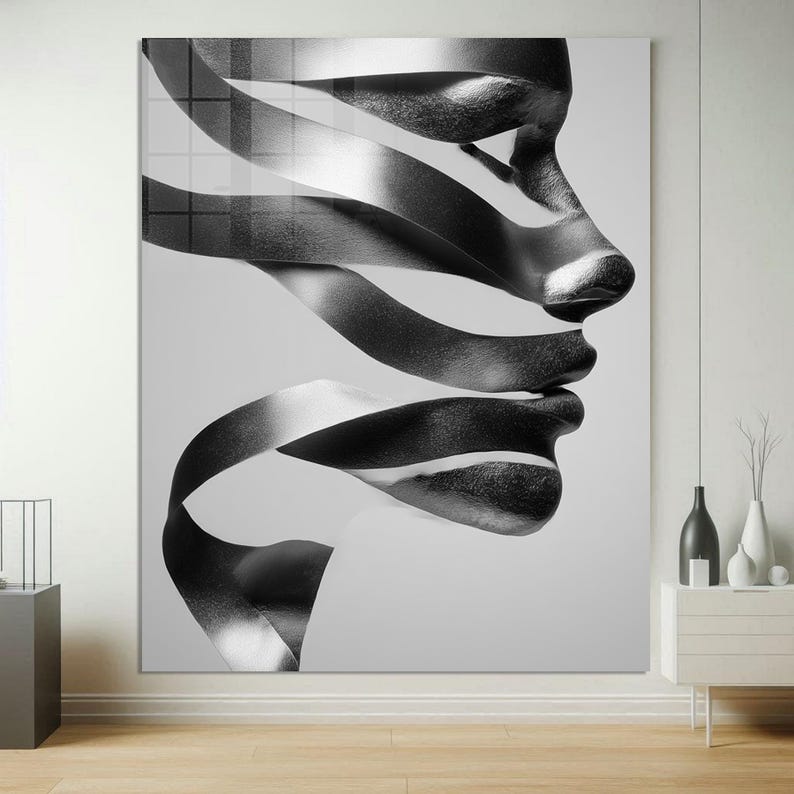 May include: Black and white abstract art print featuring a profile of a face with ribbon-like elements. The artwork is a modern piece with a grayscale color palette, suitable for contemporary home decor. The image is a large, framed canvas.