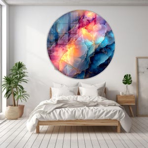 Pu&ograve; includere: Un'opera d'arte murale rotonda con un design astratto. L'opera presenta un vivace mix di colori, tra cui blu, rosa, arancione e oro. Il design assomiglia a una vista ravvicinata di una formazione di gemme. L'arte &egrave; montata sopra un letto.