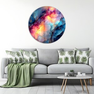 Pu&ograve; includere: Un'opera d'arte murale rotonda con un design astratto. L'opera presenta una miscela di colori, tra cui blu, rosa, arancione e oro, creando un effetto visivo dinamico. Il pezzo &egrave; montato su una parete bianca.