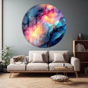 Pu&ograve; includere: Un'opera d'arte murale rotonda con un design astratto nei toni del blu, rosa e giallo, con dettagli dorati. L'opera &egrave; esposta sopra un divano beige in un soggiorno, creando un'estetica moderna. Il diametro &egrave; di circa 100 cm.