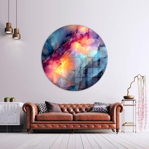 Pu&ograve; includere: Un'opera d'arte murale rotonda con un design astratto nei toni del blu, rosa, arancione e oro. L'opera ha un aspetto simile a un acquerello o a una gemma. &Egrave; montata su una parete bianca sopra un divano in pelle marrone. Un elemento decorativo per il soggiorno.
