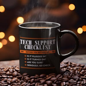 May include: A black coffee mug with a white design that says "Tech Support Checklist" and includes a list of questions: "Is it plugged in?", "Is it turned on?", "Are you sure?", "Seriously, go check."