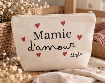 May include: A cream-colored canvas zippered pouch featuring the black text Mamie d'amour and the name lizio in a script font. The pouch is decorated with five small red hearts arranged around the central text on the front side.