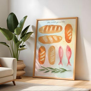 May include: A framed watercolour print depicting different loaves of bread and two pink fish. The words "he will provide" are at the top. The artwork is in a wooden frame and leans against a white wall.