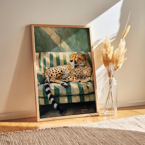 May include: A framed art print featuring a cheetah resting on a green and white striped sofa. The cheetah has a spotted coat and is lying down. The artwork is in a wooden frame, and the scene is illuminated by sunlight.
