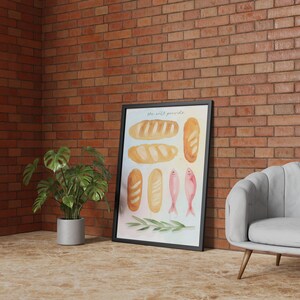 May include: A framed watercolour print depicting different types of bread, fish, and olive branches. The artwork is set against a brick wall, with a potted plant and a grey armchair. The print includes the text "the wild pantry".