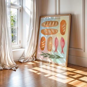 May include: A framed watercolour print depicting different types of bread and pink fish. The gold-coloured frame leans against a wall. The artwork includes the text "We will provide".