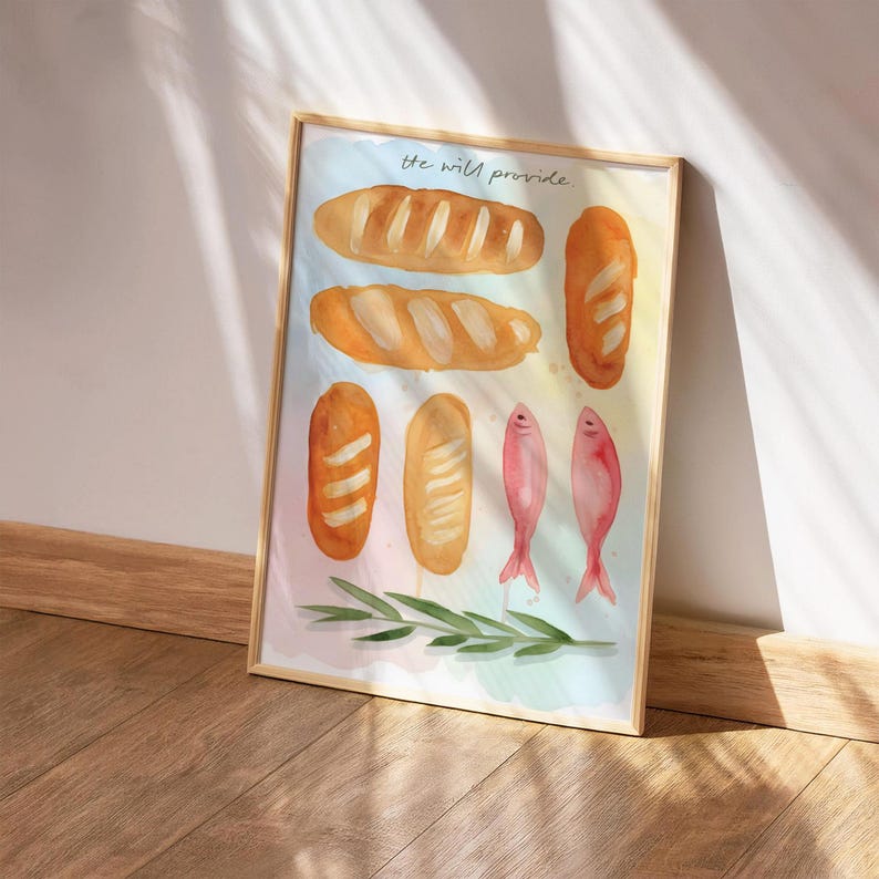 May include: A framed watercolour print depicting several loaves of bread, two pink fish, and green sprigs. The text "the wild provide" is written in cursive. The frame is made of light wood.