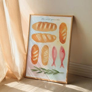 May include: Framed watercolour print depicting several bread loaves, two pink fish, and a green sprig. The cursive text at the top reads "he will provide". The background has a soft, colourful gradient.