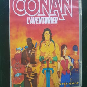 May include: A DVD case for the animated series "Conan the Adventurer." The cover art shows a group of cartoon characters, including Conan, set against a fiery orange and yellow backdrop. The title "CONAN" is in large white letters.