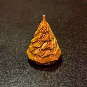 May include: A small, gold-colored, 3D printed Christmas tree ornament with a geometric design.
