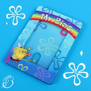 Op de afbeelding: Een blauw en regenboog fotolijst met een cartoonfiguur aan de voorkant. De lijst zegt "My Bias" en heeft een uitsparing voor een foto.