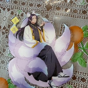 May include: An anime-style acrylic figure featuring a character with long black hair, fox ears, and a large, fluffy, multi-toned purple tail. The character is wearing a white and black outfit with gold accents. The figure has Japanese text in the upper left corner.