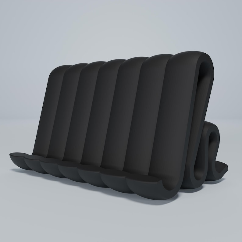 May include: Black phone stand made of flexible, ribbed material. The stand is shaped like a wave and has five slots for holding phones.