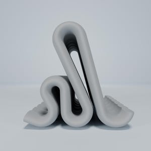 May include: A gray, folded, abstract sculpture made of a smooth, rubber-like material. The sculpture is folded into a series of loops and curves, creating a unique and interesting shape.
