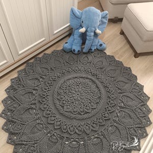 May include: A gray crocheted round rug with a large circular pattern in the center. The rug has a delicate, lacy design and is perfect for adding a touch of handmade charm to any room.