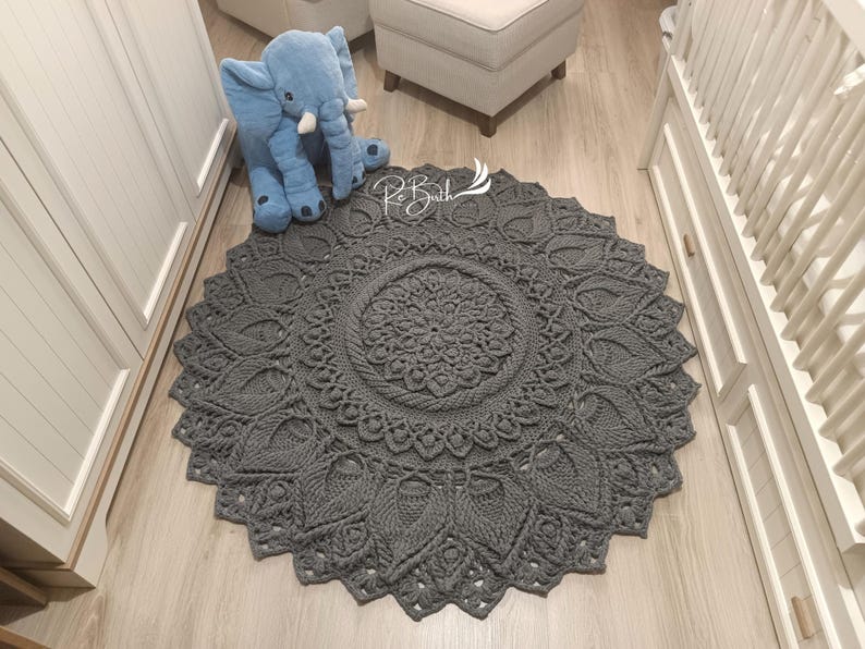 May include: A gray crocheted round rug with a mandala design. The rug has a delicate, intricate pattern and is perfect for adding a touch of bohemian style to any room.
