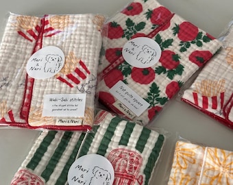 Può includere: Cinque panni in tessuto rettangolari in confezioni di plastica trasparente, con vari motivi tra cui pomodori rossi, fiori gialli, strisce verdi con sardine e patatine fritte. Ogni panno ha un adesivo circolare Mari & Nari.