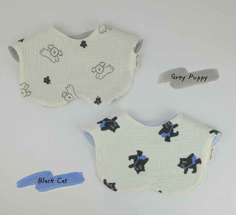 Pu&ograve; includere: Due bavaglini arrotondati con superficie in tessuto testurizzato. Il bavaglino superiore &egrave; bianco sporco con stampa di cuccioli grigi e fiori, etichettato Grey Puppy. Il bavaglino inferiore &egrave; bianco sporco con stampa di gatti neri con borse blu, etichettato Black Cat.