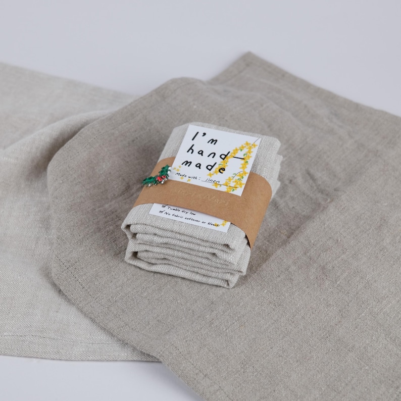 May include: A stack of four linen tea towels folded and tied with a brown ribbon. The label reads "I'm hand made with linen".