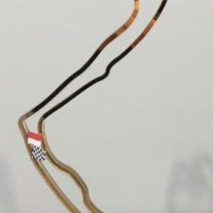 Puede incluir: Un trofeo dorado con forma de circuito de carreras, con una bandera a cuadros en blanco y negro y la bandera de Mónaco. El trofeo tiene un emblema circular con una corona. La base es azul oscuro con letras doradas que dicen "GRAND PRIX DE MONACO F1".