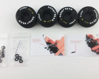 May include: Four black Goodyear Eagle tires with white lettering, along with small bags of hardware and instruction cards. The tires are for a model car or similar item. The text on the tires reads "GOOD YEAR" and "EAGLE".